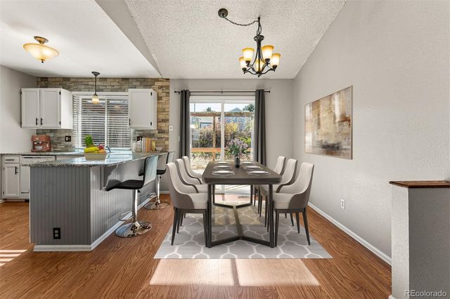 a dining room with wooden floor and a chandelier