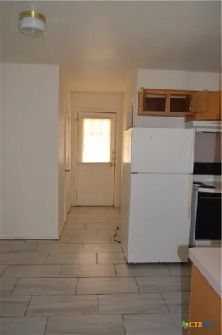 a view of a kitchen with a refrigerator a stove top oven and cabinets