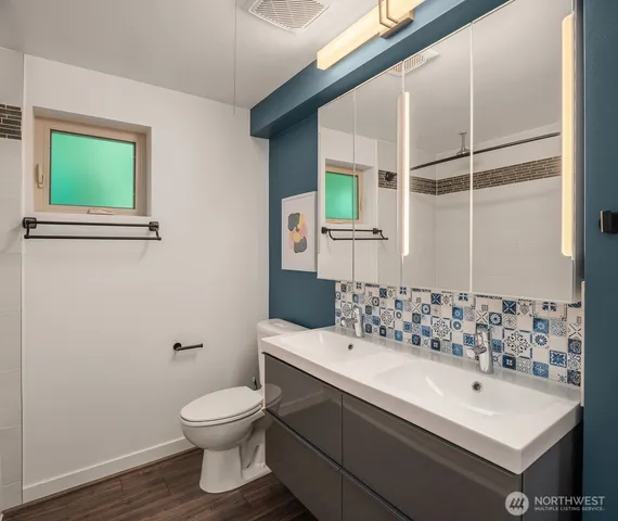 a bathroom with a sink mirror toilet and next to a window