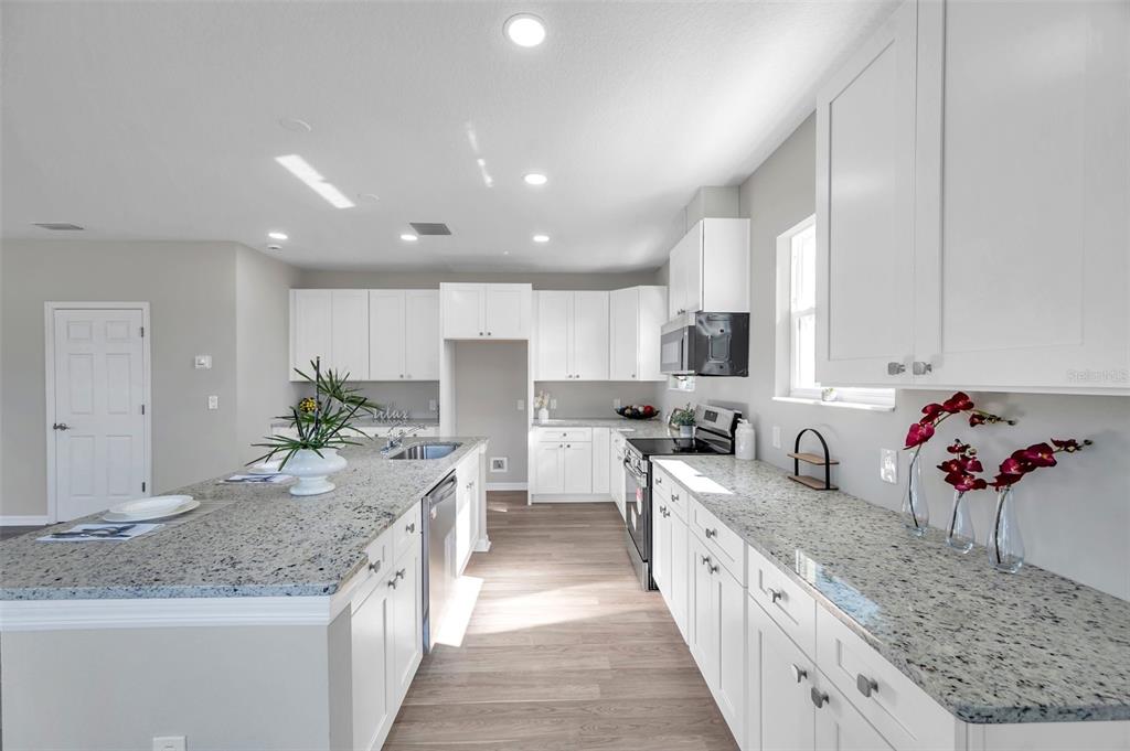 5742 Meadowlane Street New Port Richey, FL 34652 - Photo 11 of 88 a large kitchen with stainless steel appliances kitchen island granite countertop a sink and cabinets