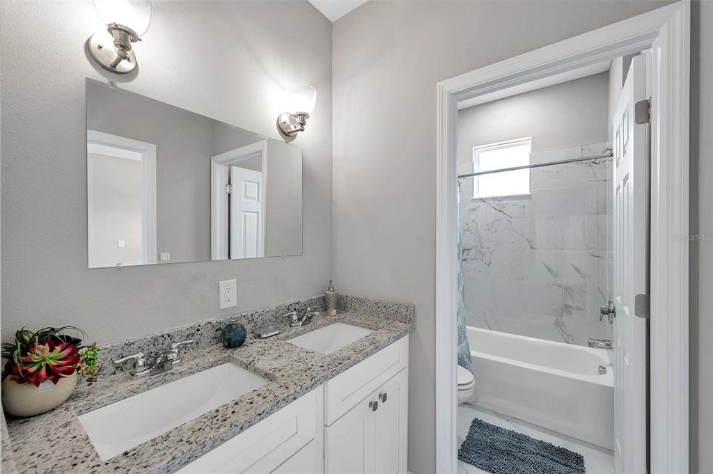 5742 Meadowlane Street New Port Richey, FL 34652 - Photo 28 of 88 a bathroom with a granite countertop sink a toilet and shower