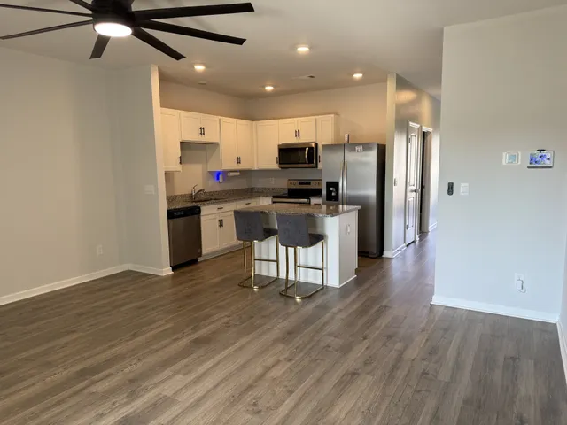 a kitchen with a sink stainless steel appliances and wooden floor