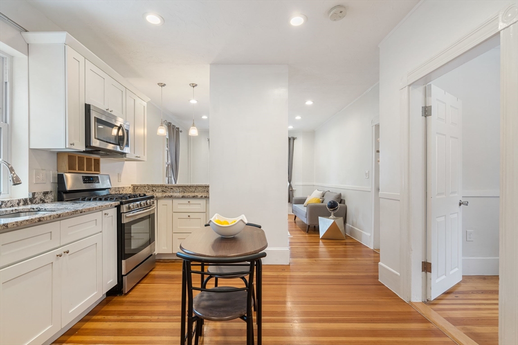 23 Goethe Street, Unit 1 Boston, MA 02132 - Photo 3 of 19 a kitchen with stainless steel appliances a dining table chairs stove and cabinets