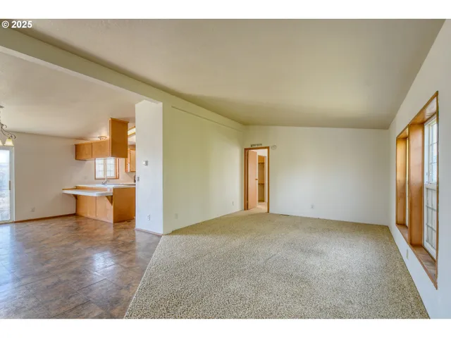 a view of empty room with wooden floor and windows