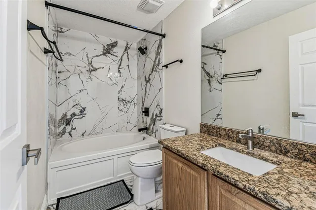 a bathroom with a granite countertop sink toilet and shower
