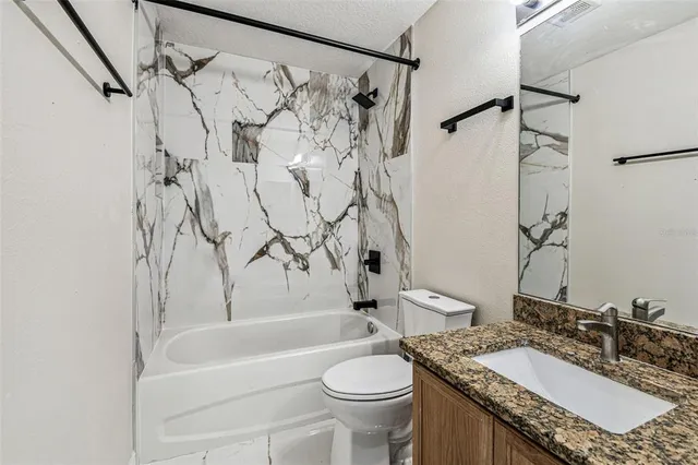 a bathroom with a granite countertop sink toilet and shower