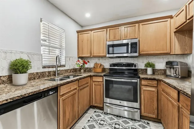 a kitchen with granite countertop a sink stove and microwave