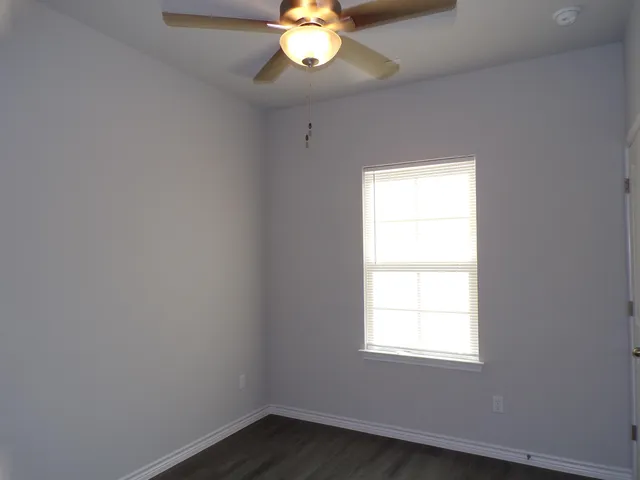 an empty room with a window and a chandelier fan
