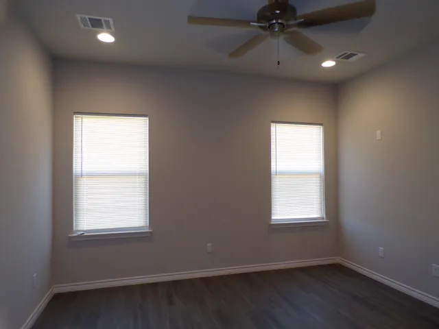 an empty room with a window and a fan