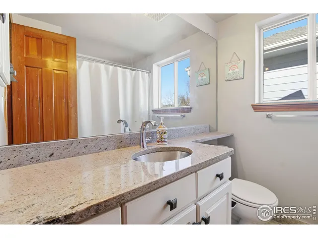 a bathroom with a granite countertop sink a mirror and a toilet