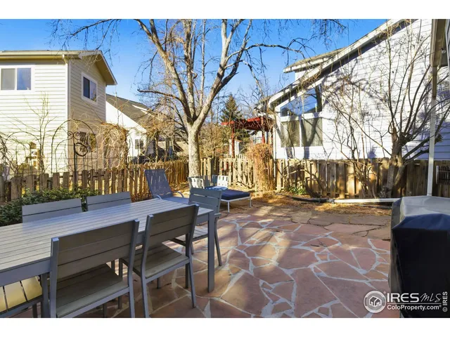 a view of a patio with table and chairs with wooden fence and large trees