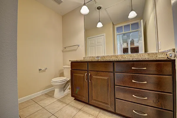 a bathroom with a granite countertop toilet sink and mirror