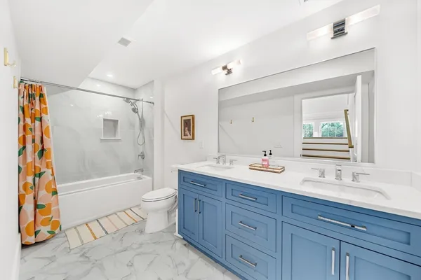 a bathroom with a double vanity sink toilet mirror and bathtub