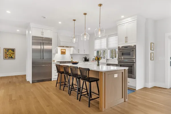 a kitchen with stainless steel appliances granite countertop a refrigerator a sink dishwasher a stove and white cabinets with wooden floor