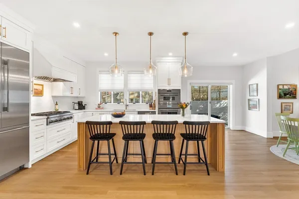 a kitchen with stainless steel appliances granite countertop a dining table chairs and white cabinets