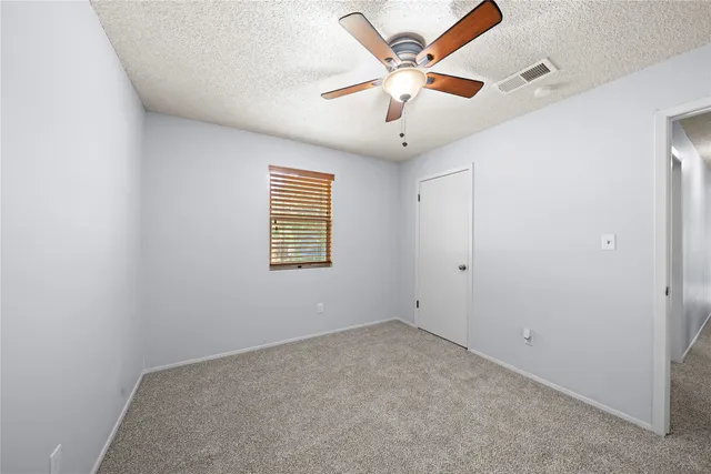 an empty room with a window and a fan