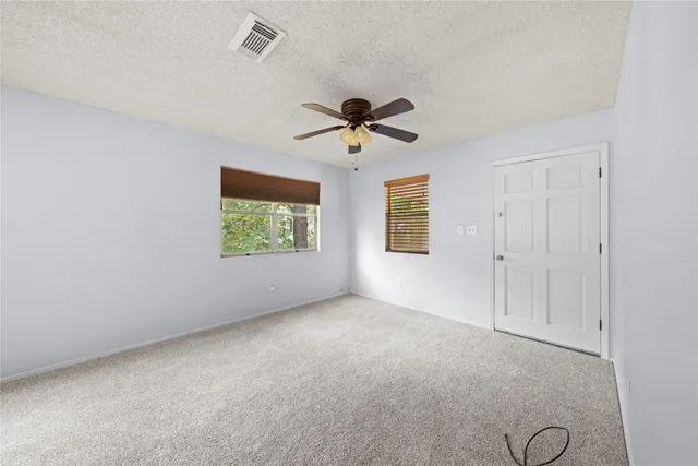 an empty room with windows and fan