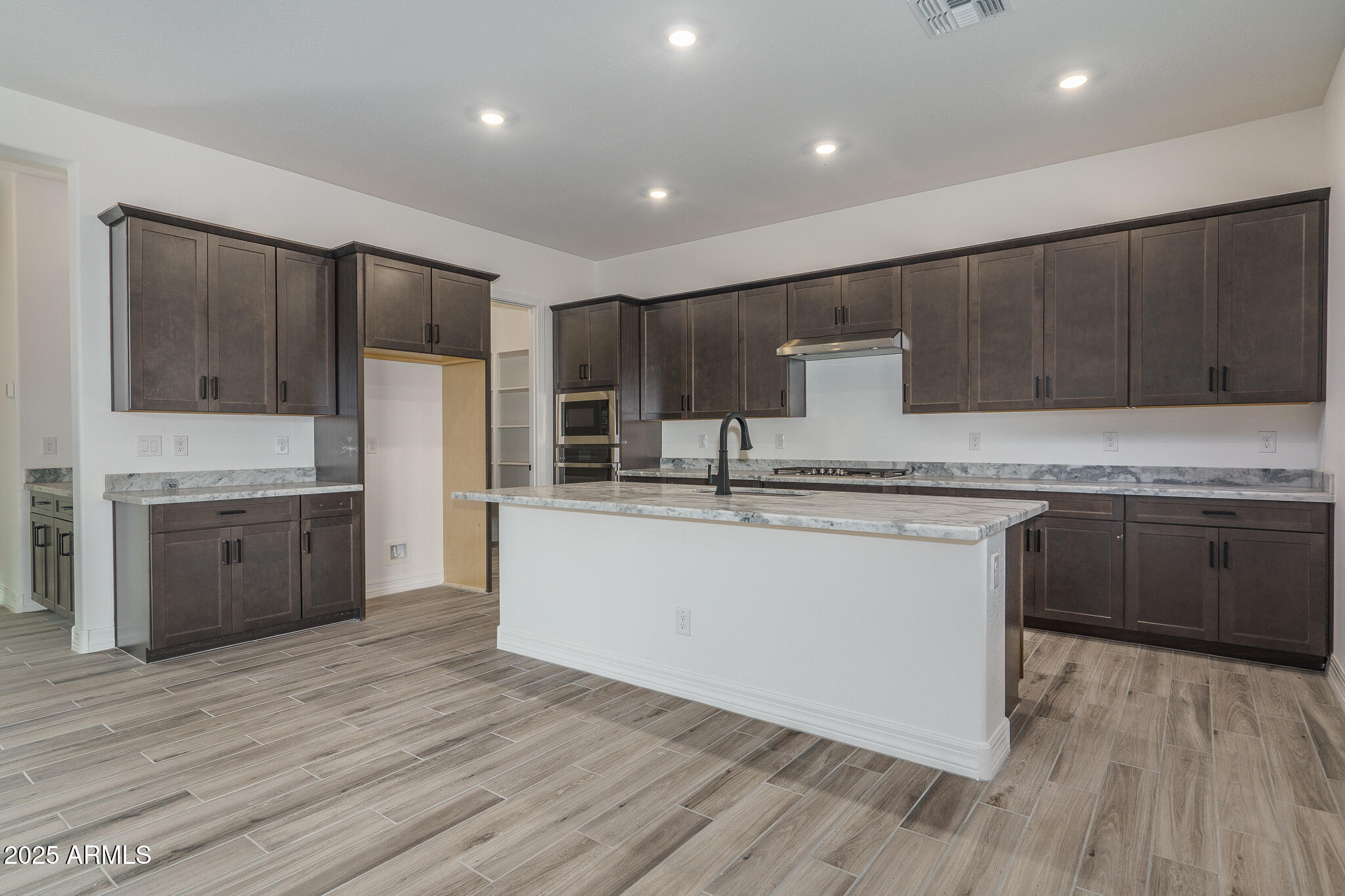 18575 West Sapium Way Goodyear, AZ 85338 - Photo 11 of 51 a kitchen with kitchen island granite countertop wooden floors stainless steel appliances a sink and cabinets