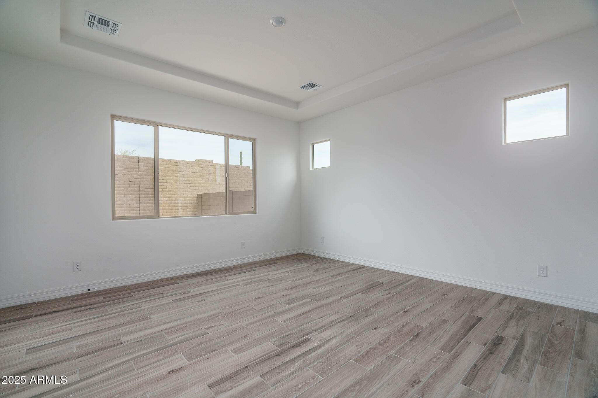 18575 West Sapium Way Goodyear, AZ 85338 - Photo 16 of 51 an empty room with wooden floor and windows