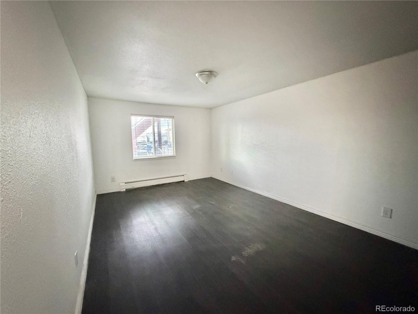1080 South Eliot Street, Unit 202 Denver, CO 80219 - Photo 5 of 8 an empty room with wooden floor and windows
