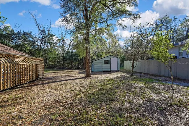 a view of a small house with a large tree and wooden fence