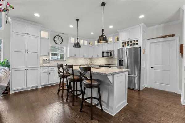 a large kitchen with cabinets a island a sink stainless steel appliances and wooden floor