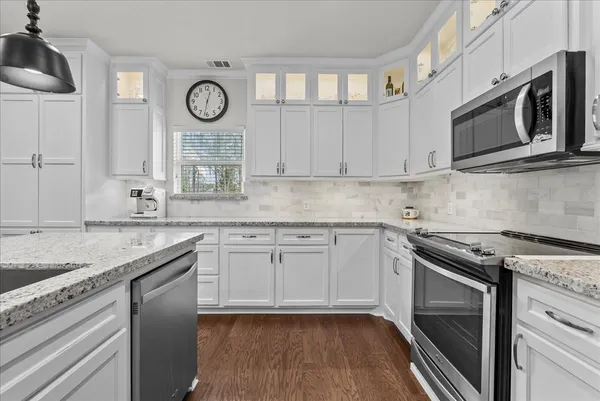 a kitchen with stainless steel appliances granite countertop a stove and a wooden floors