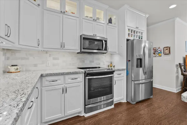 a kitchen with stainless steel appliances granite countertop a stove top oven a refrigerator a sink and chairs