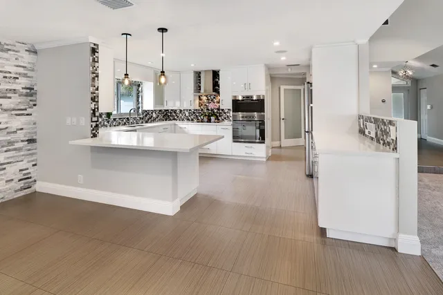 a large white kitchen with stainless steel appliances