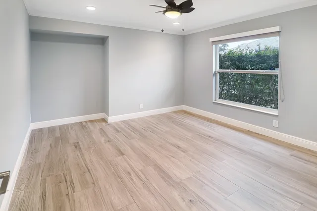 a view of an empty room with window and wooden floor