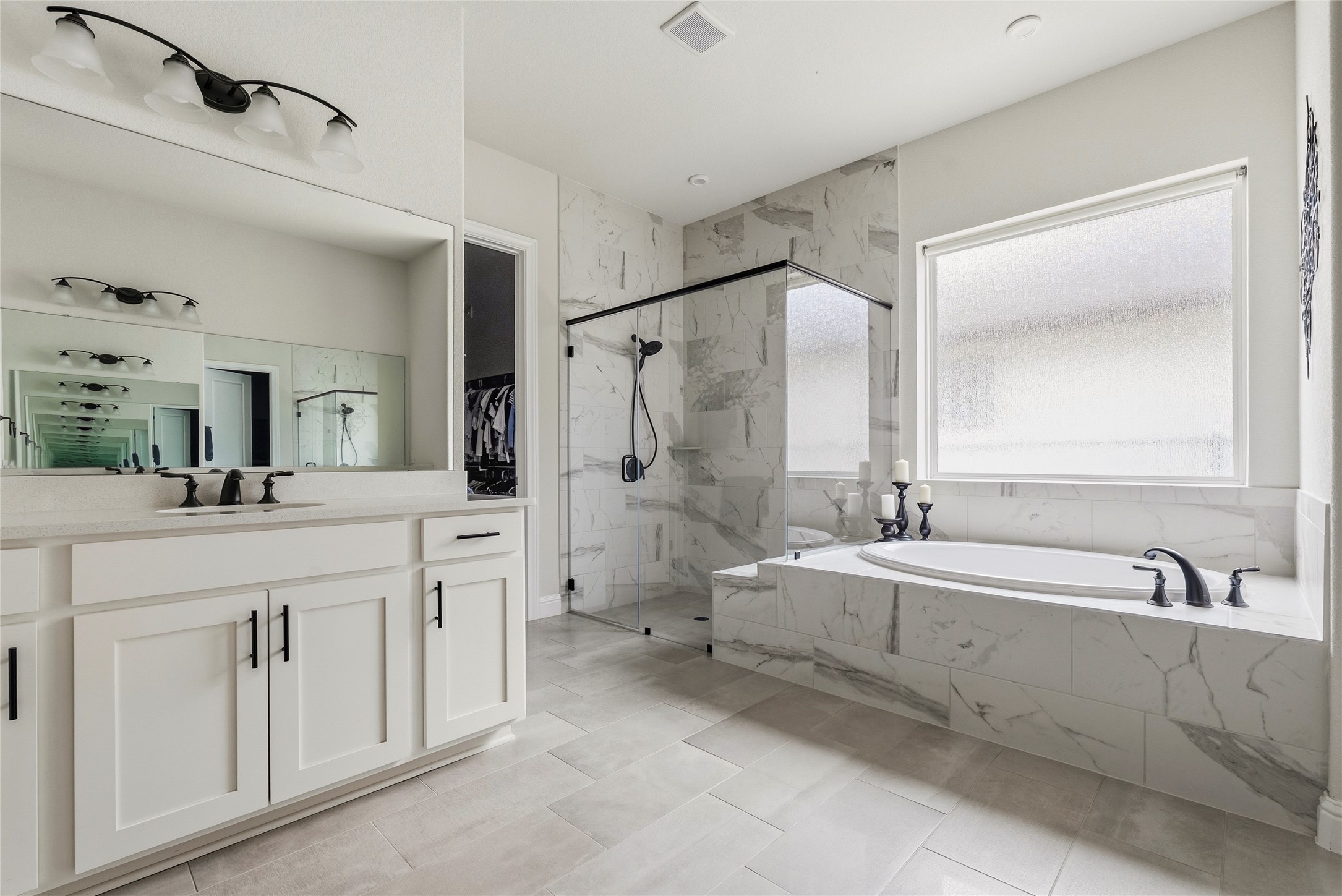 4513 Vieste View Leander, TX 78641 - Photo 29 of 40 Spacious bathroom featuring a built-in soaking tub, a large walk-in shower with glass enclosure, white vanity with dual sinks, and light-toned tile flooring