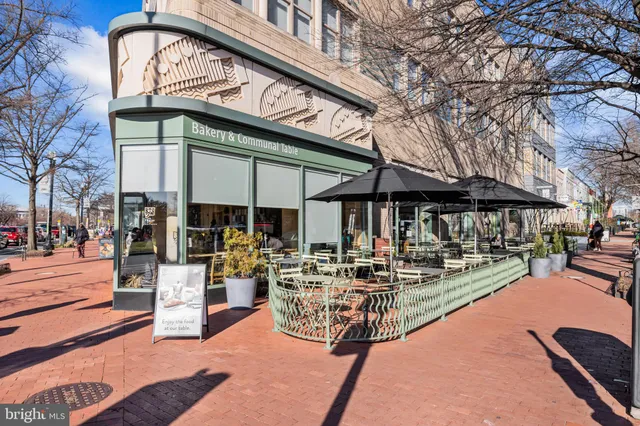 a view of a patio with dining table and chairs under an umbrella with a small yard