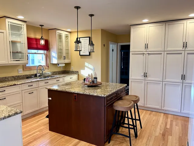 a kitchen with stainless steel appliances granite countertop a sink a stove a refrigerator and island with wooden floor