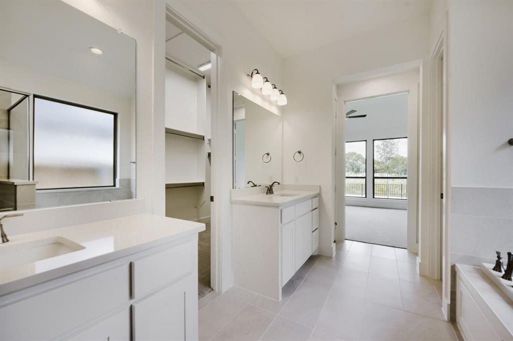 11465 Wulstone Road Fort Worth, TX 76052 - Photo 15 of 27 Bright bathroom featuring dual vanity sinks with white cabinetry and light countertops, a walk-in shower with clear glass enclosure, a built-in bathtub, and an adjacent walk-in closet with shelving