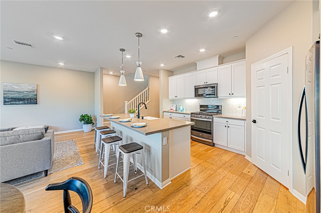 1705 Almond Tree Place Upland, CA 91784 - Photo 4 of 41 a kitchen with stainless steel appliances kitchen island granite countertop a refrigerator a stove a sink dishwasher a dining table and chairs with wooden floor
