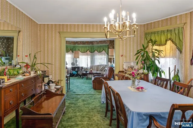 a view of a dining room with furniture a chandelier and large windows