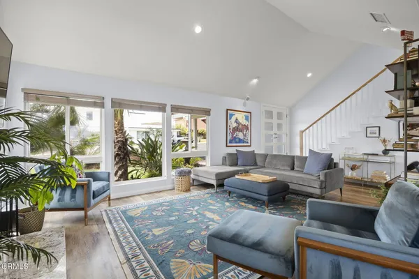 a kitchen with granite countertop a refrigerator a sink a stove and white cabinets with wooden floor