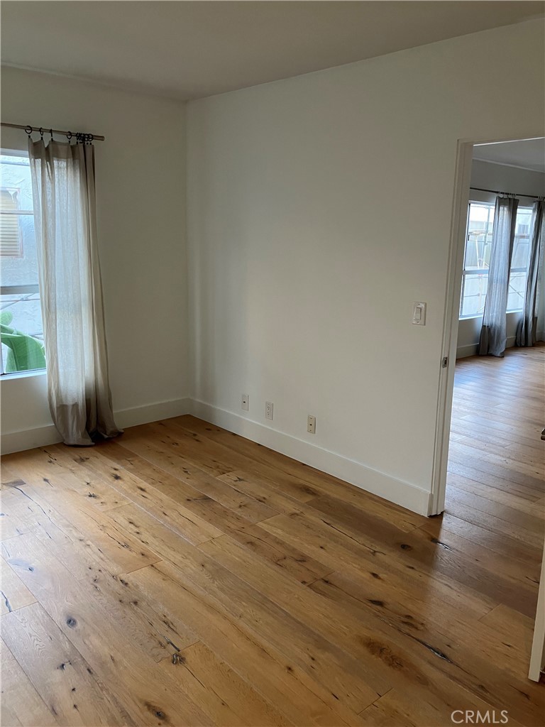 8811 Burton Way, Unit 202 Los Angeles, CA 90048 - Photo 9 of 19 an empty room with wooden floor and windows