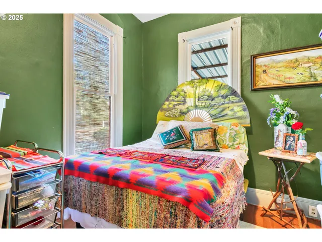 a bedroom with a bed a computer on the table and a lamp