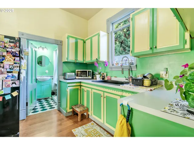 a kitchen with a refrigerator a sink dishwasher and a dining table with garden view