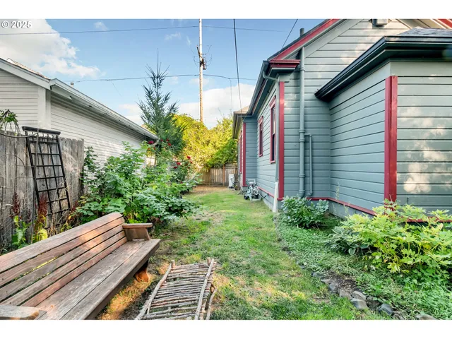 a yellow house with flower garden and wooden fence