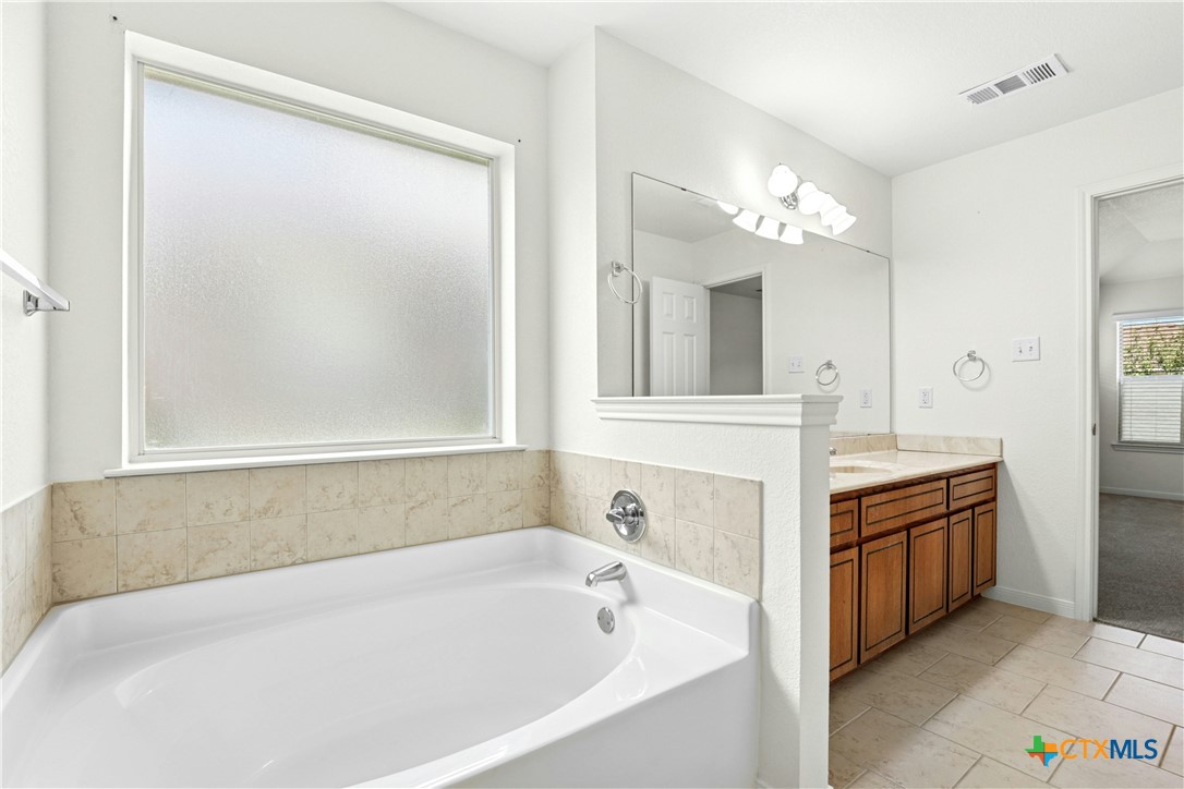 3203 Canadian River Loop Killeen, TX 76549 - Photo 18 of 27 a bathroom with a bathtub a double vanity sink and a mirror