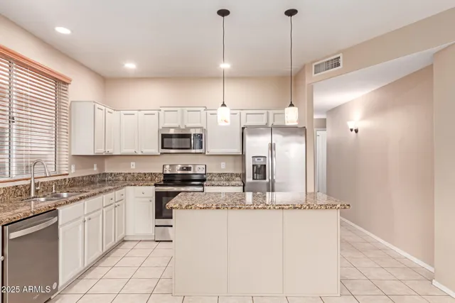 a kitchen with stainless steel appliances granite countertop a sink a stove a refrigerator and island with wooden floor