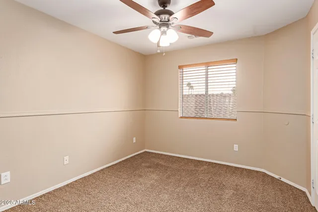 an empty room with a window and a fan