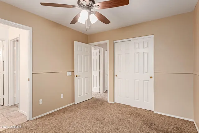 an empty room with closet and a chandelier fan