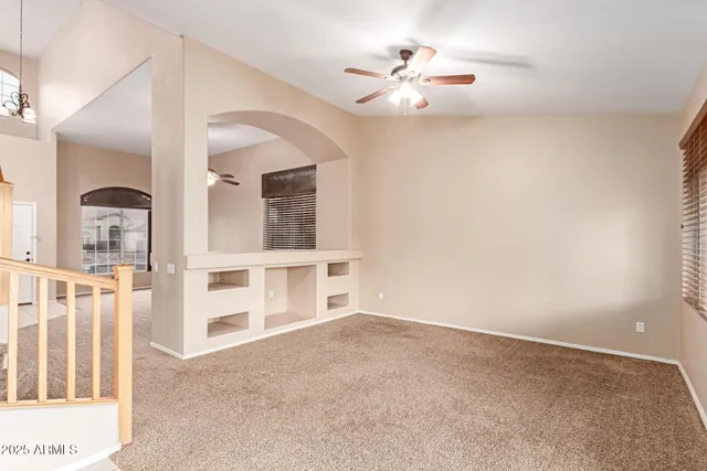 an empty room with windows and ceiling fan