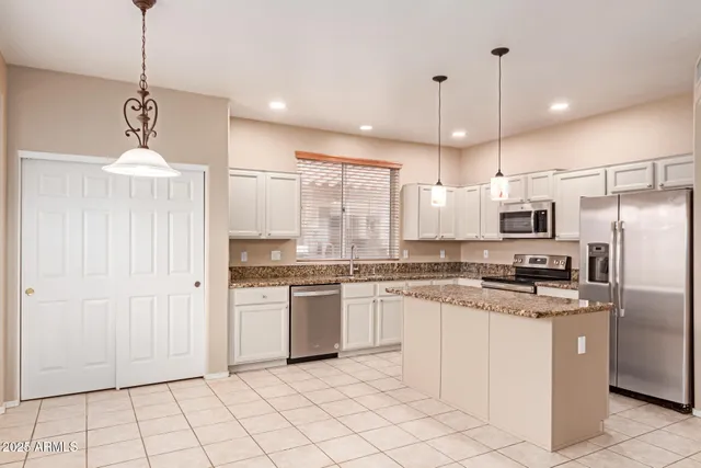 a kitchen with kitchen island granite countertop stainless steel appliances cabinets a sink and a counter top