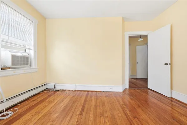 a view of an empty room with wooden floor and a window