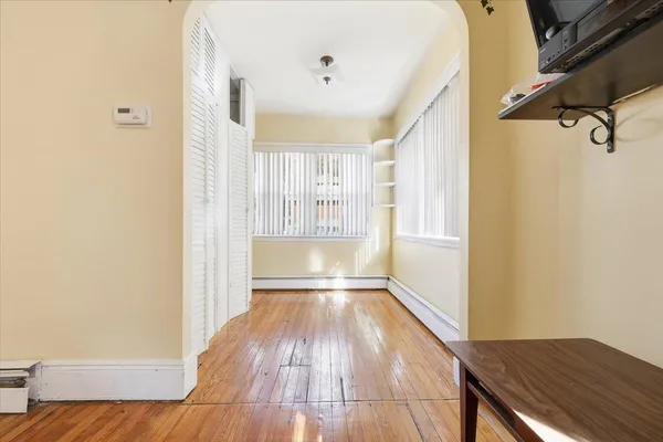 a view of an empty room with wooden floor and a window