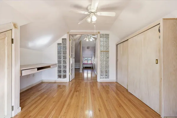 a view of empty room with wooden floor and fan